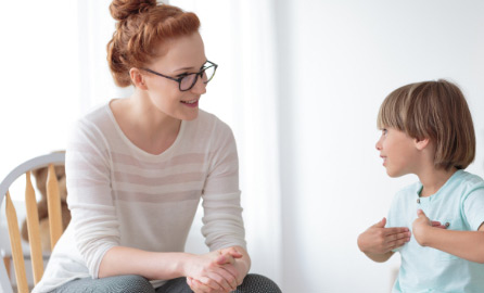Auf dem Bild ist eine sitzende Frau zu sehen, die einem redendem Kind zuhört.